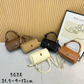 Five handbags in different colors arranged on a surface with a Picasso poster in the background.