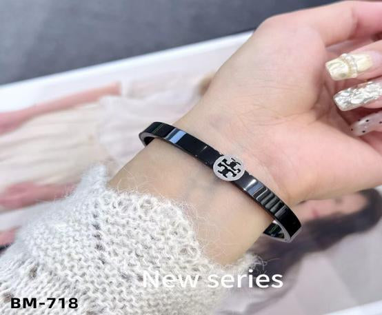 Black bracelet with a logo worn on a wrist, with 'new series' text and 'BM-718' code.