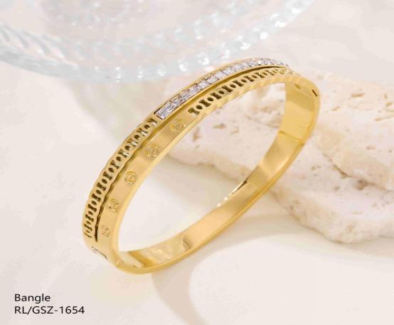 Gold bangle with embedded stones on a light background