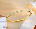 Gold bangle with diamond accents on a white surface