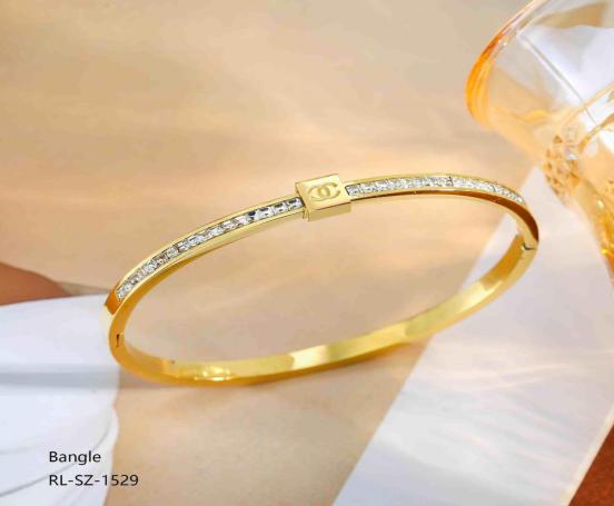 Gold bangle with diamond accents on a white surface