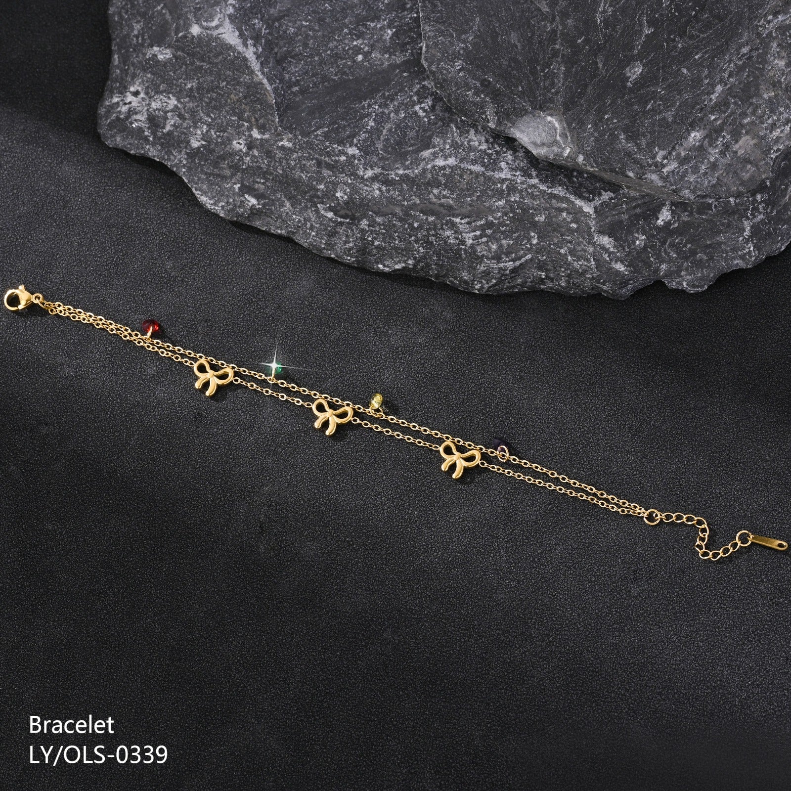 Gold bracelet with bow-shaped charms on a dark surface
