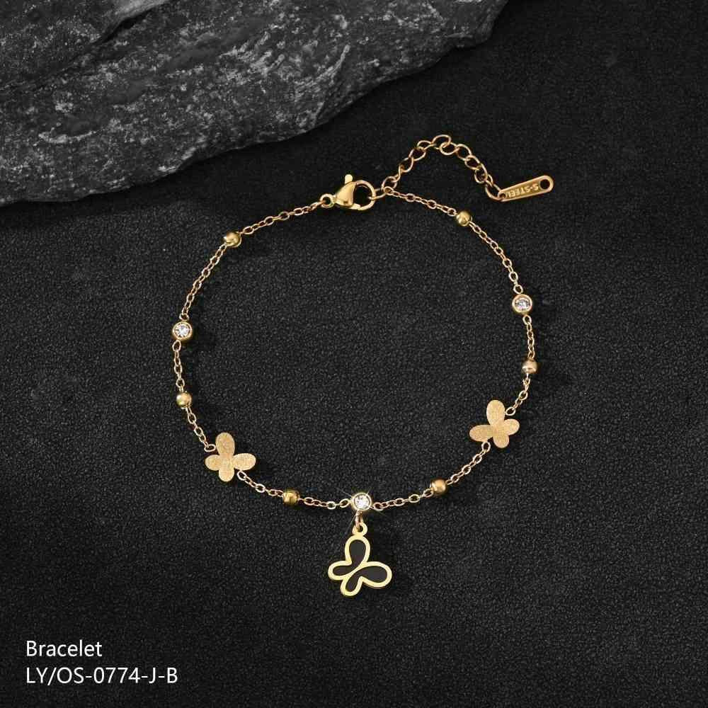 Gold bracelet with butterfly charms on a dark surface