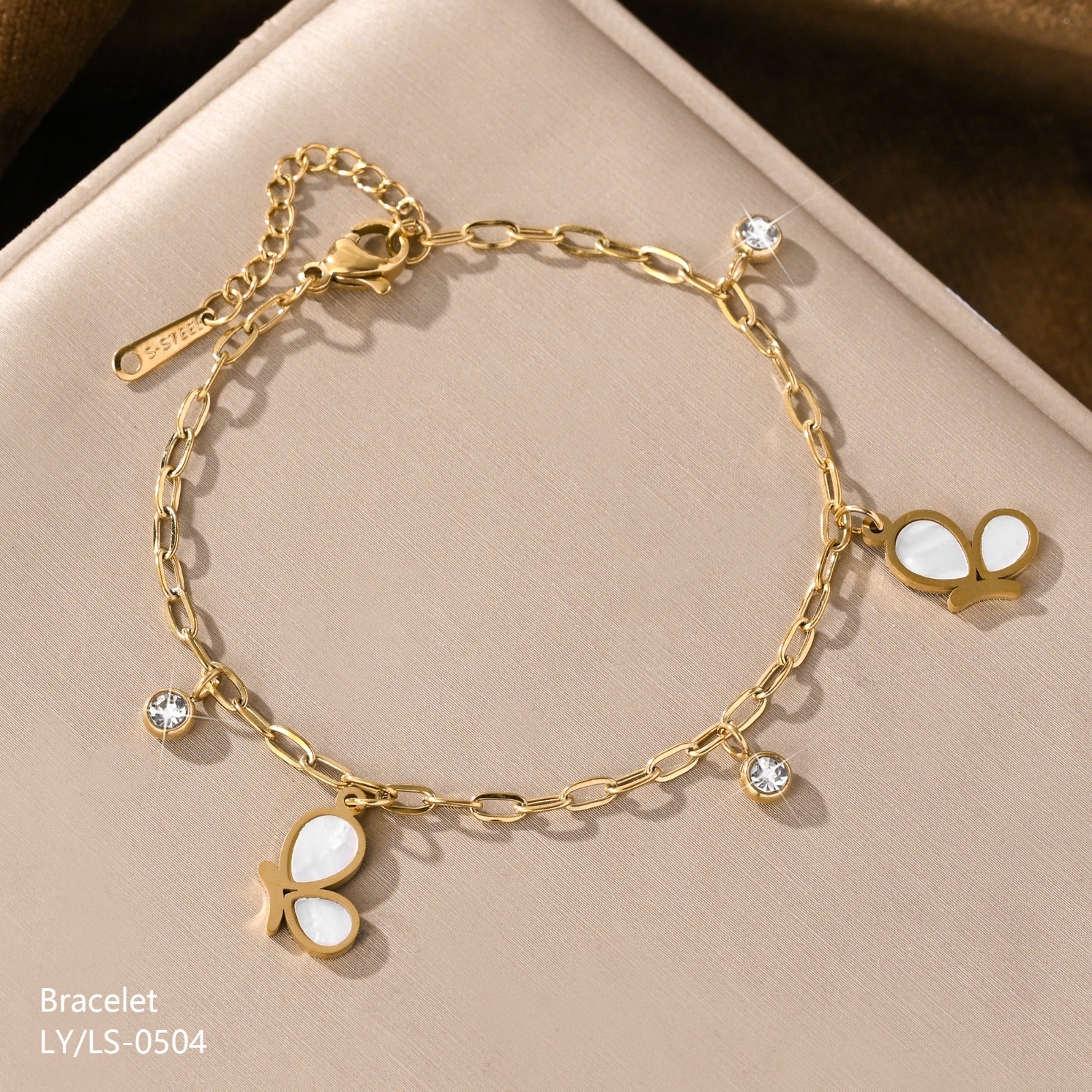 Gold bracelet with butterfly charms on a beige background