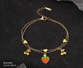Gold bracelet with strawberry and cherry charms on a dark background