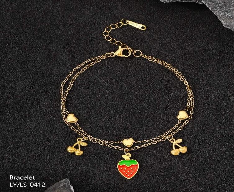 Gold bracelet with strawberry and cherry charms on a dark background