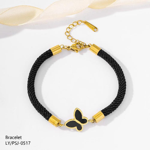 Black braided bracelet with gold accents and a butterfly charm on a white background