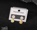 Flower-shaped earrings on a stainless steel card against a dark background