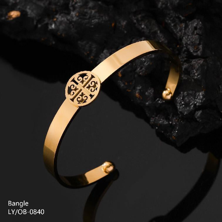Gold bangle with intricate design on a dark background