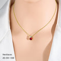 Gold necklace with a red pendant on a mannequin